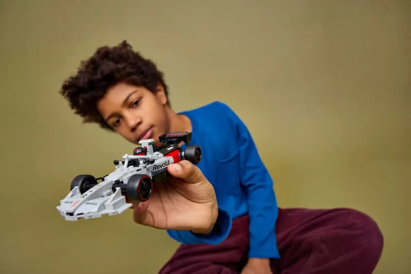 A young person holding the assembled LEGO Audi Revolut F1 Team R26 Race Car 77259, showcasing its portable size and playability.