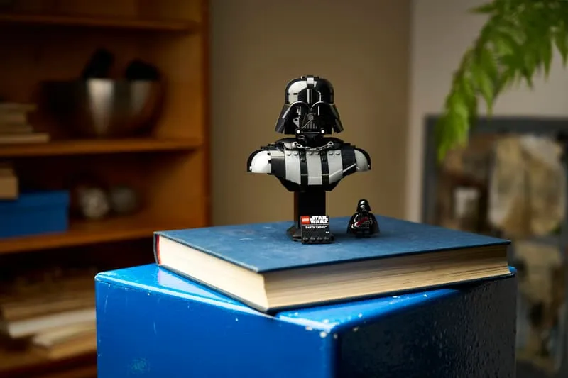 The Lego Darth Vader Bust 75439 placed atop a stack of blue and red books, demonstrating its compact size and versatility for display in various settings.