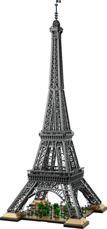 Front, slightly low-angle view of the completed LEGO Eiffel Tower 10307 model, showing its full height and the detailed base with trees.