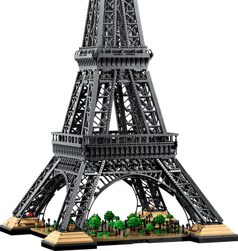 Close-up view of the base of the LEGO Eiffel Tower 10307 model, showing the surrounding parkland with numerous green trees and detailed walkways.