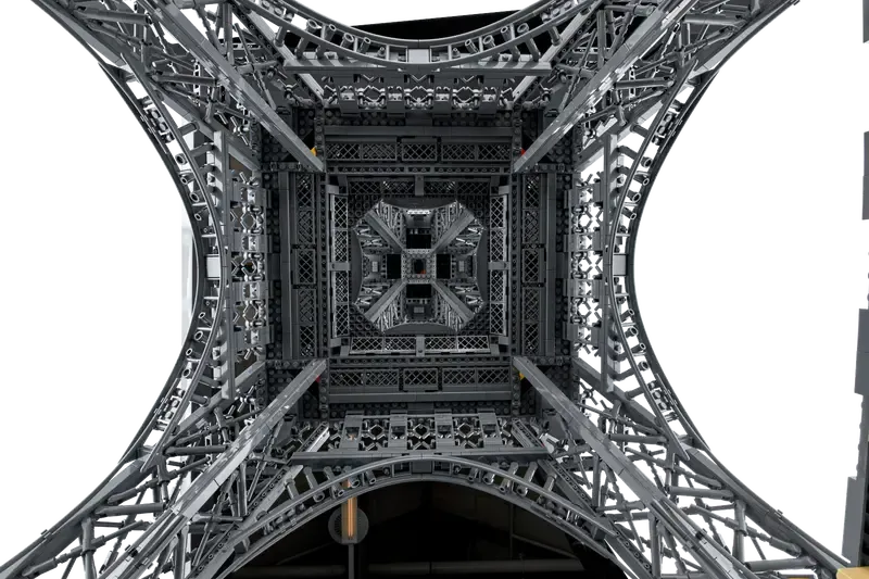 View looking directly upwards from within the base of the LEGO Eiffel Tower 10307 model, showcasing the intricate symmetrical lattice work extending upwards.