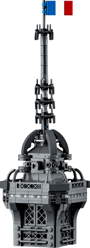 Close-up view of the intricate spire and antenna of the LEGO Eiffel Tower 10307 model, topped with a small French flag.