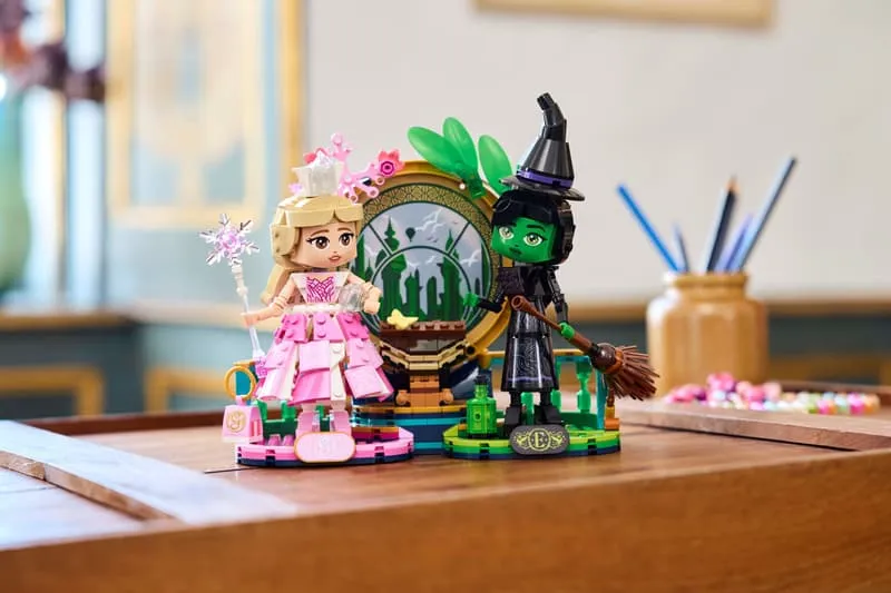 The Lego Elphaba & Glinda figures set beautifully displayed on a wooden table in a well-lit room, showcasing its aesthetic appeal as a collector's item.