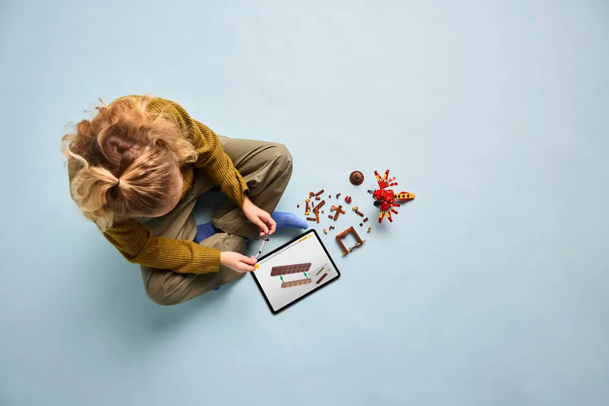Overhead view of child building with digital instructions.