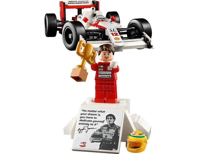 Close-up of the Ayrton Senna Lego minifigure holding a trophy, standing on his display base with a quote and helmet.