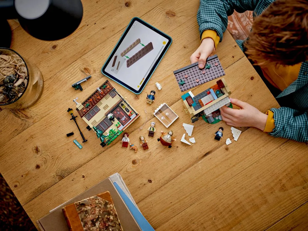 Child's hands building LEGO Privet Drive.