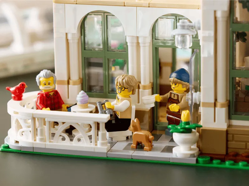 Exterior close-up of Lego The Botanical Garden 21353, showing minifigures enjoying a cafe area on a balcony.