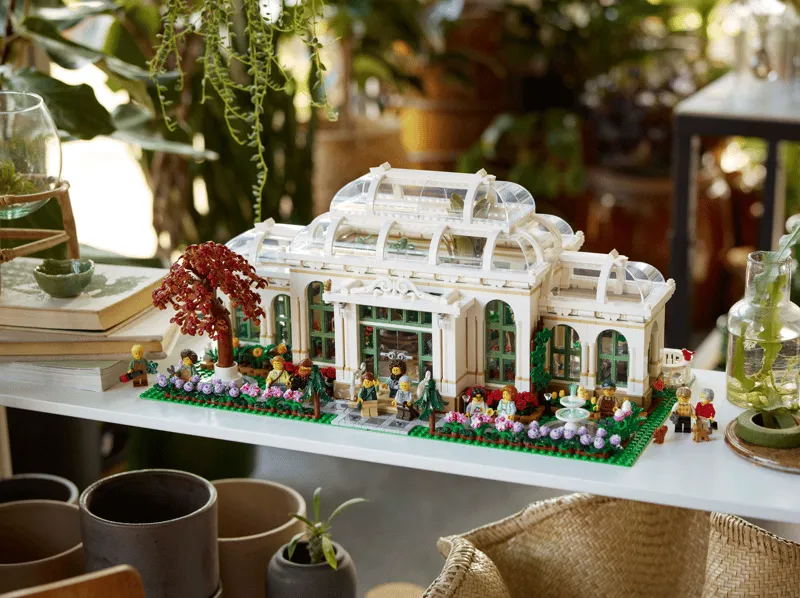 The assembled Lego The Botanical Garden 21353 set displayed on a white shelf surrounded by real plants and decorative items.
