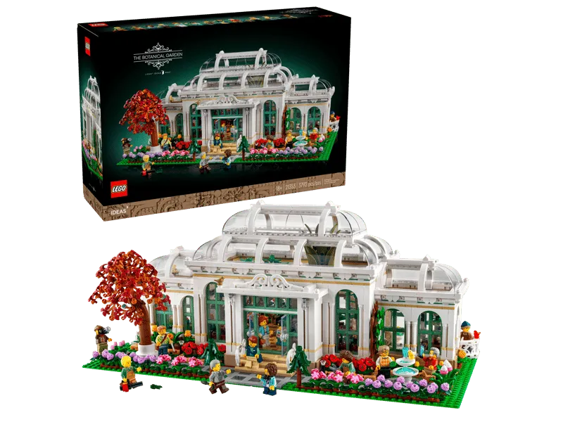 The Lego The Botanical Garden 21353 set fully assembled next to its product box, showcasing the complete greenhouse and surrounding garden.