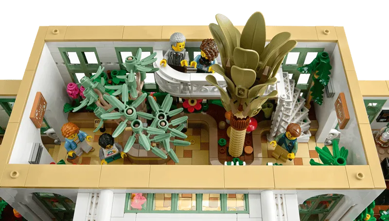 Overhead interior view of Lego The Botanical Garden 21353, showcasing a diverse collection of brick-built plants and minifigures on an upper balcony.