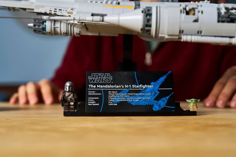 Close-up of the Lego N-1 Starfighter UCS display plaque with technical specifications, The Mandalorian minifigure, and Grogu minifigure.