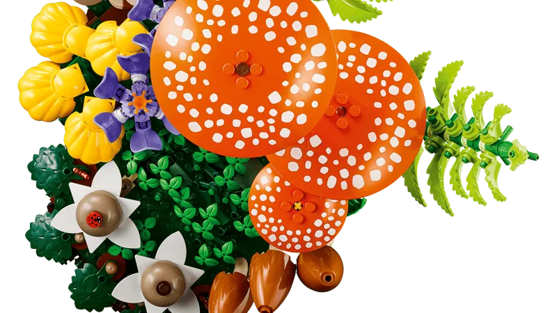 A close-up, top-down view of the LEGO Woodland Mushrooms set, highlighting the details of the orange mushroom caps with white spots, purple and yellow flowers, and a tiny red ladybug piece on a white flower.