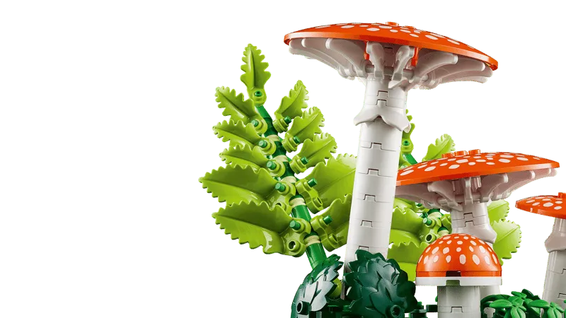 A close-up shot of the white stems and red caps of the larger Fly Agaric mushrooms, alongside bright green fern elements, emphasizing the structural details and natural forms.